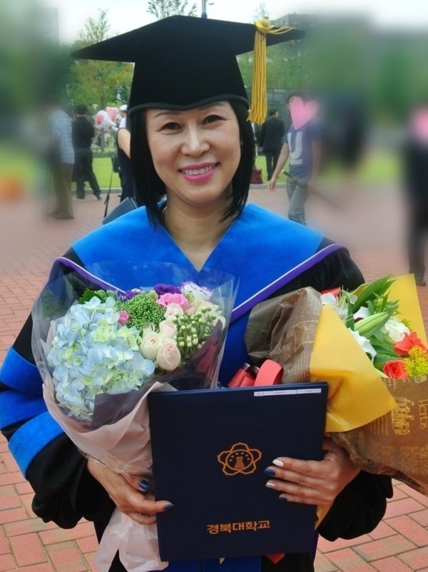 학위복을 입고 학위기를 든 엄명자